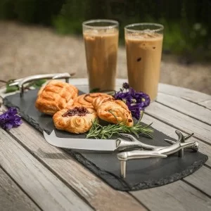 Small slate tray with antler handles on table with coffees and cakes